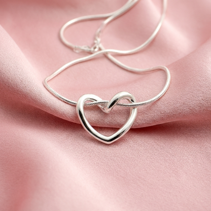 Серебряное колье в форме сердца на розовой пастели