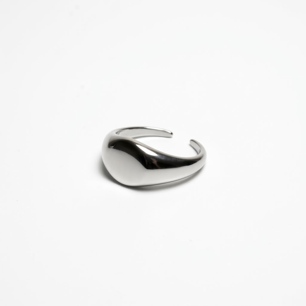 A single gold stud earring with a clear gemstone, shown in profile against a solid off-white background.